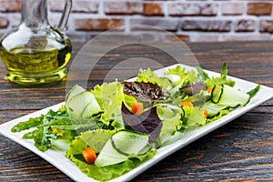 Fresh green salad in a plate with spinach, arugula, romance carrots, on a vintage wooden table. Natural healthy food