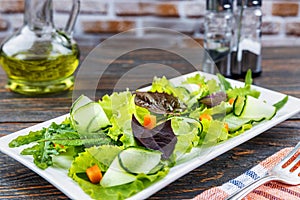 Fresh green salad in a plate with spinach, arugula, romance carrots, on a vintage wooden table. Natural healthy food