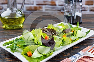 Fresh green salad in a plate with spinach, arugula, romance carrots, on a vintage wooden table. Natural healthy food