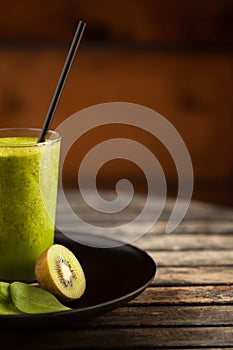 Fresh green smoothie on the plate at wooden table