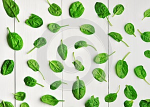 Fresh green spinach leaves pattern over white wooden table background. Vegan food trend