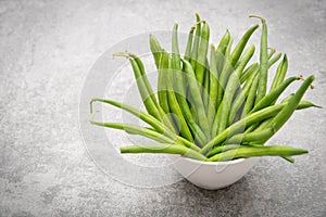 Fresh green string beans on a plate isolated on a grey structured background