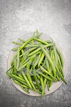 Fresh green string beans on a plate isolated on a grey structured background