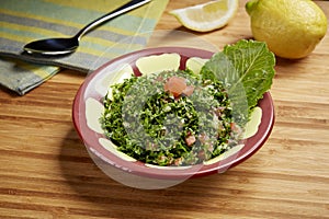 Fresh green Taboule or tabbouleh with tomato, green leaf and lime slice served in dish isolated on table side view of middle east