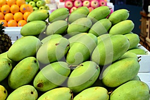 Fresh green unripe mango fruits symmetrically to attract buyers at market stall photo