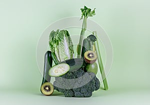 Fresh green vegetables and fruits on green background. Equilibrium floating food balance