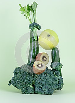 Fresh green vegetables and fruits on green background. Equilibrium floating food balance