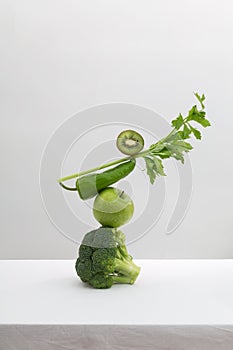 Fresh green vegetables and fruits on white table. Equilibrium floating food