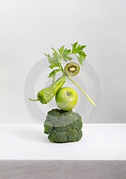 Fresh green vegetables and fruits on white table. Equilibrium floating food