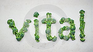 Fresh green veggies spell vital on grey surface