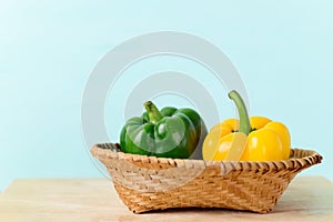 Fresh green and yellow bell peppers in a bamboo basket