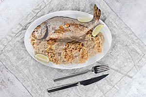 Fresh grilled dorado or sea bream fish with lemon and rosemary served with rice. Delicous dorada fish cooked on grill in seafood