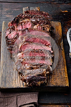 Fresh grilled meat. Grilled beef steak medium rare black angus rib eye steak, on wooden serving board, on old dark  wooden table