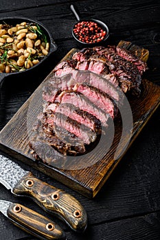 Fresh grilled meat. Grilled beef steak medium rare black angus rib eye steak, on wooden serving board, with white beans and