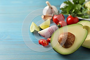 Fresh guacamole ingredients on light blue wooden table. Space for text