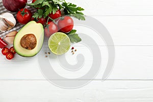 Fresh guacamole ingredients on white wooden table, flat lay. Space for text