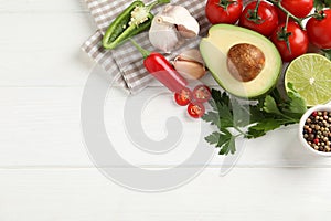 Fresh guacamole ingredients on white wooden table, flat lay. Space for text