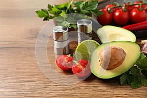 Fresh guacamole ingredients on wooden table. Space for text