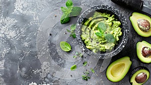 A fresh guacamole in a stone bowl, surrounded by ripe avocados and herbs on a textured gray surface.