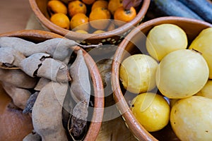 Fresh guavas, hawthorns, and tamarind in clay bowls