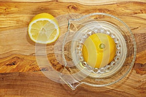 Fresh half lemon on glass juicer on a wooden board. Juice is on the bottom of jar. Close up. Top down view