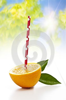 Fresh half orange with drinking straw on white background