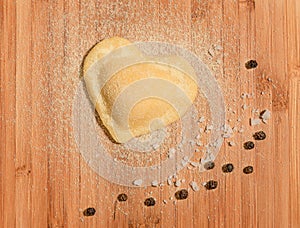 Fresh,handmade single raviolo in the shape of heart with few grains of black pepper and coarse salt.