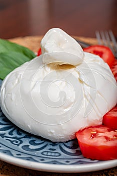 Fresh handmade soft Italian cheese from Puglia, white ball of burrata foglia saporosa or burratina cheese made from mozzarella and photo