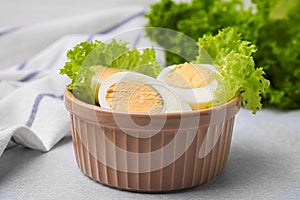 Fresh hard boiled eggs and lettuce on light grey table, closeup