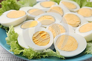 Fresh hard boiled eggs and lettuce on white wooden table, closeup