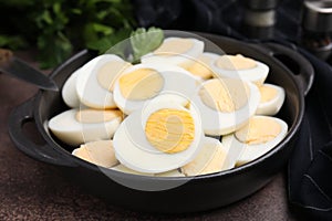 Fresh hard boiled eggs and parsley on brown table, closeup