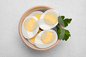 Fresh hard boiled eggs and parsley on light grey table, top view