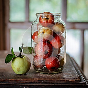 Fresh harvest of ripe and healthy farm apples in a glass jar, in a basket.