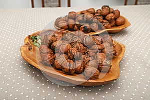 Fresh harvest walnuts with shells and water drops in wooden bowl. Walnuts details