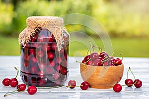 Fresh harvested red cherries and preserved fruit in jar