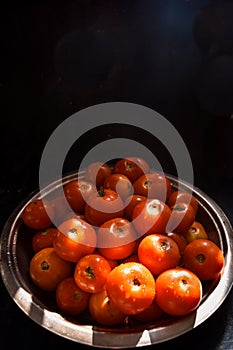 Fresh harvested sunkissed ripe red tomatoes kept in a rustic steel plate in a sunny place in kitchen. tomatoes for sauce, chutney