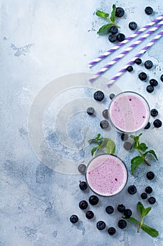 Fresh healthy blueberries smoothie berries and mint in glass on light white concrete background.