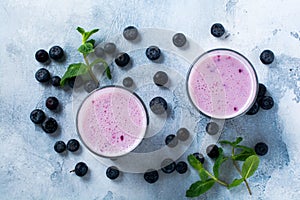 Fresh healthy blueberries smoothie berries and mint in glass on light white concrete background.