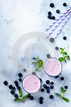 Fresh healthy blueberries smoothie berries and mint in glass on light white concrete background.