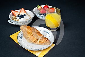 Fresh healthy breakfast with berries and croissant on a dark background