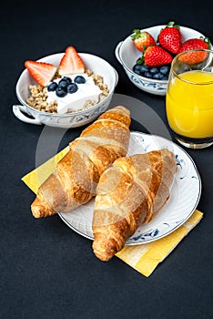 Fresh healthy breakfast with berries and croissant on a dark background