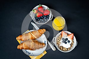 Fresh healthy breakfast with berries and croissant on a dark background