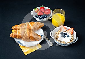 Fresh healthy breakfast with berries and croissant on a dark background