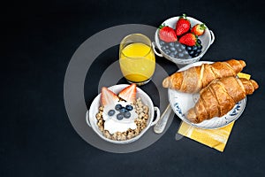 Fresh healthy breakfast with berries and croissant on a dark background