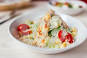 Fresh healthy caesar salad with chicken on white wooden table with fork and knife. Top view. Selective focus