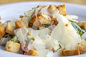 Fresh healthy Caesar salad with grilled chicken breast in a big white plate.