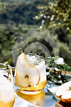 Fresh and healthy cocktail or mocktail with pear, ice and herbs on the steel tray. Refreshing drink in the garden.