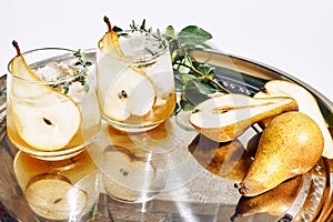 Fresh and healthy cocktail or mocktail with pear, ice and herbs on the steel tray. Refreshing drink in the garden.