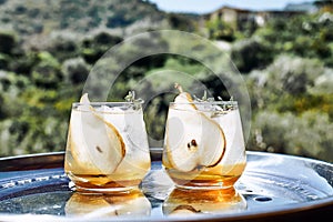 Fresh and healthy cocktail or mocktail with pear, ice and herbs on the steel tray. Refreshing drink in the garden.