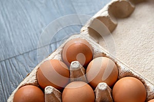 Fresh and healthy farm food. Recycked cardboard bos with brown hen eggs located on a grey wooden countertop in the kitchen. Angle